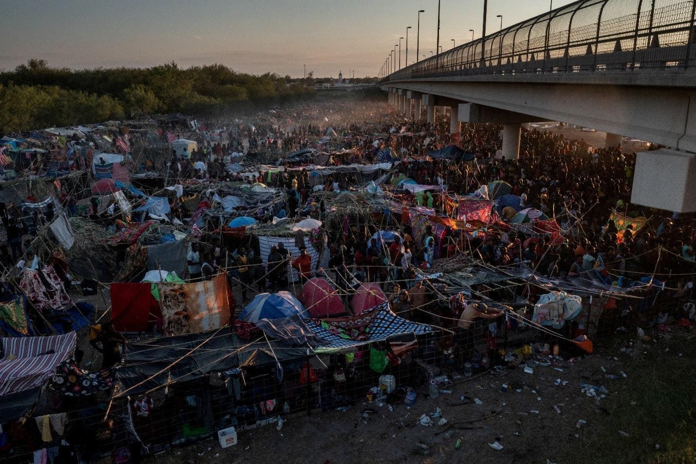 Migrants take shelter along the Del Rio International Bridge at sunset as they await to be processed after crossing the Rio Grande river into the U.S. from Ciudad Acuna in Del Rio, Texas, U.S. September 19, 2021. REUTERS/Adrees Latif